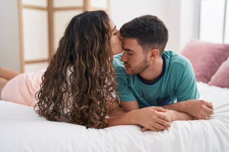 Foto de Joven pareja hispana acostada en la cama besando en el dormitorio - Imagen libre de derechos