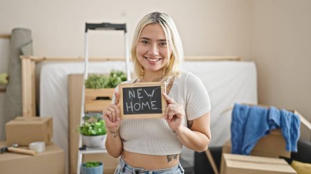 Photo for Young beautiful hispanic woman smiling confident holding blackboard at new home - Royalty Free Image