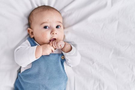 Téléchargez les photos : Adorable bébé détendu couché sur le lit dans la chambre - en image libre de droit