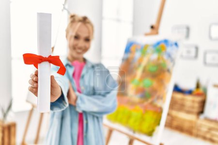 Photo for Young caucasian woman artist smiling confident holding diploma at art studio - Royalty Free Image
