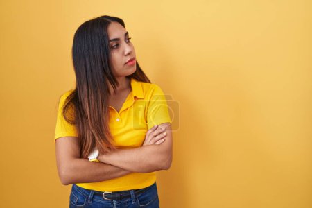 Téléchargez les photos : Jeune femme arabe debout sur fond jaune regardant sur le côté avec les bras croisés convaincus et confiants - en image libre de droit