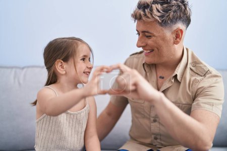 Téléchargez les photos : Père et fille père et fille faisant symbole de coeur avec les mains à la maison - en image libre de droit