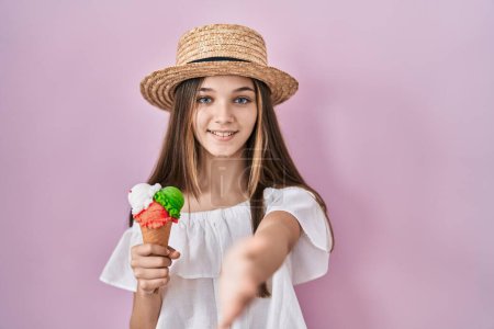 Foto de Chica adolescente sosteniendo helado sonriente amistoso ofreciendo apretón de manos como saludo y bienvenida. negocios exitosos. - Imagen libre de derechos