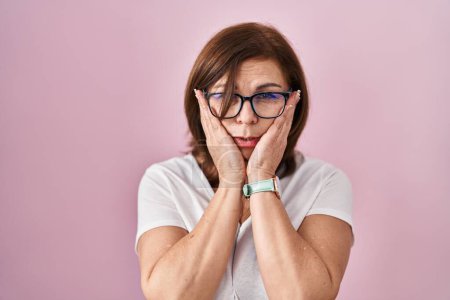 Photo for Middle age hispanic woman standing over pink background tired hands covering face, depression and sadness, upset and irritated for problem - Royalty Free Image