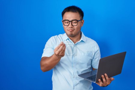 Téléchargez les photos : Chinois jeune homme utilisant ordinateur portable faisant geste d'argent avec les mains, demandant le paiement du salaire, millionnaire entreprise - en image libre de droit