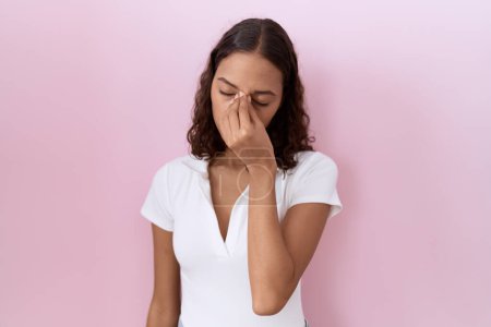 Photo for Young hispanic woman wearing casual white t shirt tired rubbing nose and eyes feeling fatigue and headache. stress and frustration concept. - Royalty Free Image