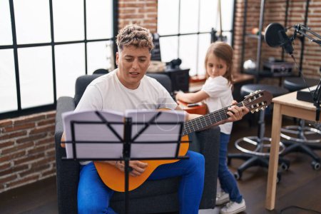 Foto de Padre e hija tocando guitarra clásica y ukelele en el estudio de música - Imagen libre de derechos