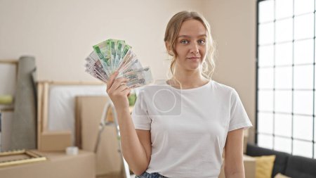 Téléchargez les photos : Jeune femme blonde tenant des roubles russes billets de banque à la nouvelle maison - en image libre de droit