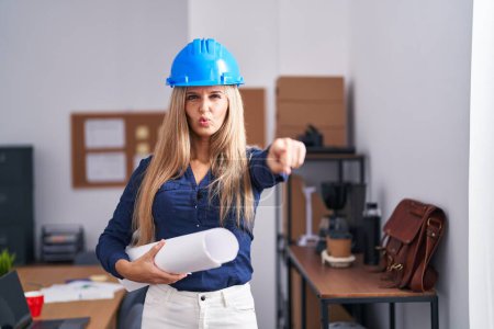Photo for Young woman wearing architect hardhat pointing with finger to the camera and to you, confident gesture looking serious - Royalty Free Image