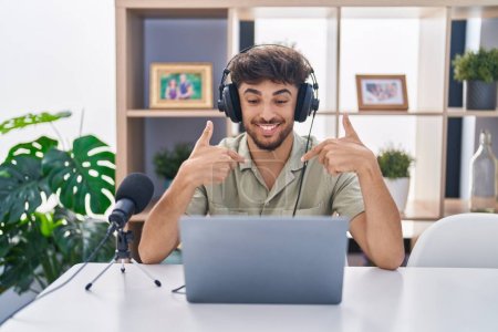 Téléchargez les photos : Homme arabe avec la barbe travaillant à la radio regardant confiant avec le sourire sur le visage, se montrant du doigt fier et heureux. - en image libre de droit