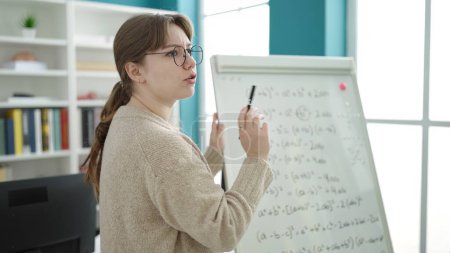 Téléchargez les photos : Young blonde woman teacher explaining maths lesson at library university - en image libre de droit