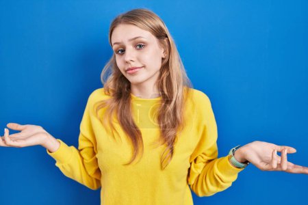 Photo for Young caucasian woman standing over blue background clueless and confused with open arms, no idea concept. - Royalty Free Image
