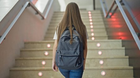 Photo for Young beautiful girl student wearing backpack climbing stairs up at school - Royalty Free Image