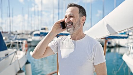 Téléchargez les photos : Moyen Age homme souriant confiant parler sur le smartphone au bateau - en image libre de droit