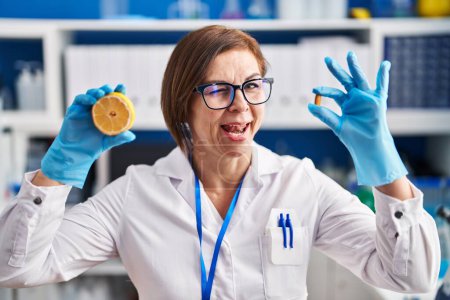 Foto de Mujer hispana de mediana edad que trabaja en el laboratorio científico haciendo guiños vitamínicos mirando a la cámara con expresión sexy, cara alegre y feliz. - Imagen libre de derechos