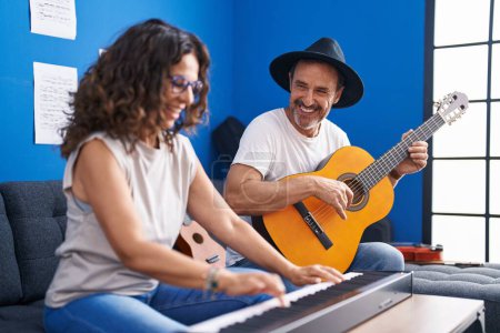 Photo for Man and woman musicians playing piano and classical guitar at music studio - Royalty Free Image
