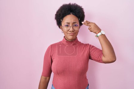 Photo for Beautiful african woman with curly hair standing over pink background shooting and killing oneself pointing hand and fingers to head like gun, suicide gesture. - Royalty Free Image