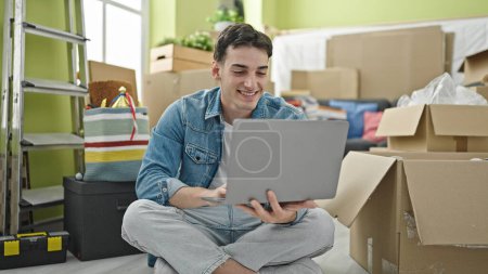 Photo for Young hispanic man using laptop sitting on floor at new home - Royalty Free Image