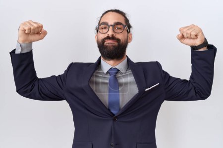 Photo for Hispanic man with beard wearing suit and tie showing arms muscles smiling proud. fitness concept. - Royalty Free Image