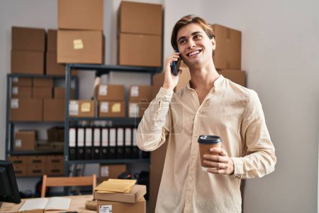 Téléchargez les photos : Young caucasian man ecommerce business worker talking on smartphone drinking coffee at office - en image libre de droit