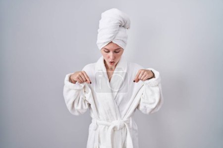 Photo for Blonde caucasian woman wearing bathrobe pointing down with fingers showing advertisement, surprised face and open mouth - Royalty Free Image