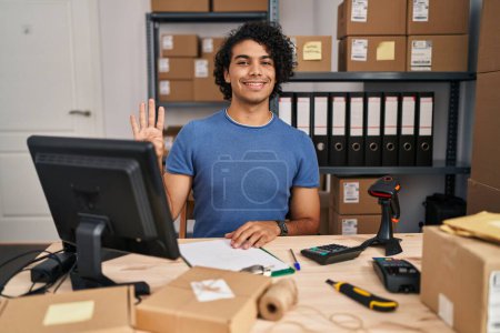 Foto de Hombre hispano con el pelo rizado trabajando en el comercio electrónico de pequeñas empresas mostrando y señalando con los dedos número cuatro mientras sonríe confiado y feliz. - Imagen libre de derechos