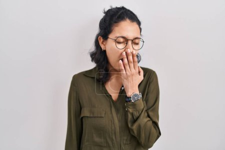 Photo for Hispanic woman with dark hair standing over isolated background bored yawning tired covering mouth with hand. restless and sleepiness. - Royalty Free Image