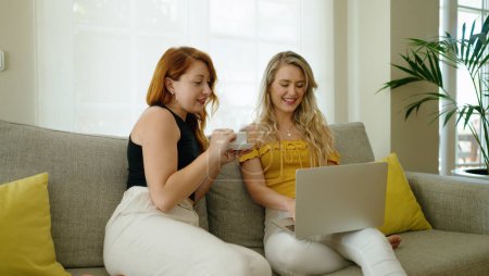 Téléchargez les photos : Deux femmes qui boivent du café avec un ordinateur portable à la maison - en image libre de droit