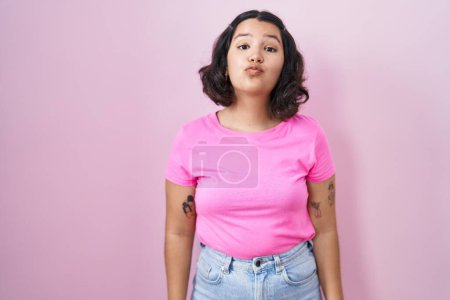 Photo for Young hispanic woman standing over pink background looking at the camera blowing a kiss on air being lovely and sexy. love expression. - Royalty Free Image