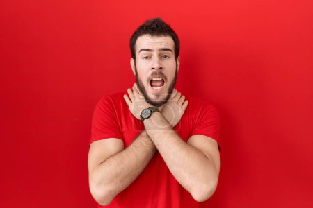 Photo for Young hispanic man wearing casual red t shirt shouting suffocate because painful strangle. health problem. asphyxiate and suicide concept. - Royalty Free Image