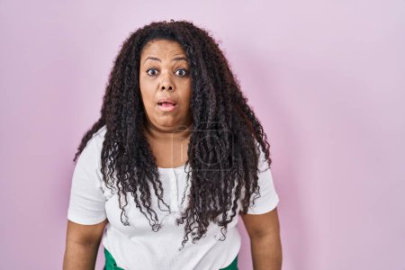 Photo for Plus size hispanic woman standing over pink background afraid and shocked with surprise and amazed expression, fear and excited face. - Royalty Free Image