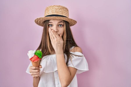 Téléchargez les photos : Adolescente tenant crème glacée choqué couvrant la bouche avec les mains pour erreur. concept secret. - en image libre de droit