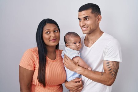 Photo for Young hispanic couple with baby standing together over isolated background smiling looking to the side and staring away thinking. - Royalty Free Image