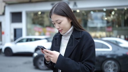 Téléchargez les photos : Young chinese woman smiling confident using smartphone at street - en image libre de droit