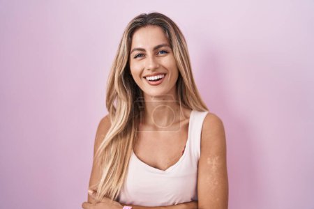 Photo for Young blonde woman standing over pink background happy face smiling with crossed arms looking at the camera. positive person. - Royalty Free Image