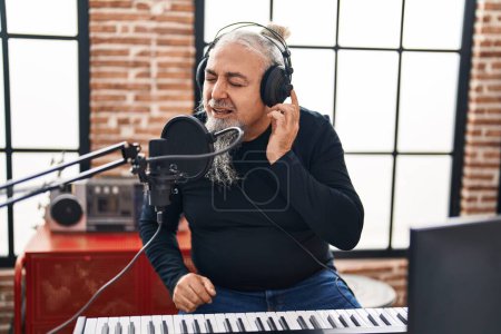 Téléchargez les photos : Moyen Age homme aux cheveux gris musicien souriant chanson de chant confiant au studio de musique - en image libre de droit