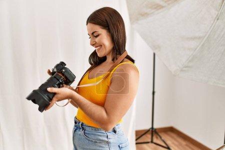 Téléchargez les photos : Jeune belle femme hispanique photographe tenant studio photo appareil photo professionnel - en image libre de droit
