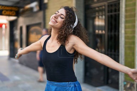 Téléchargez les photos : Jeune belle femme hispanique écoutant de la musique et dansant dans la rue - en image libre de droit