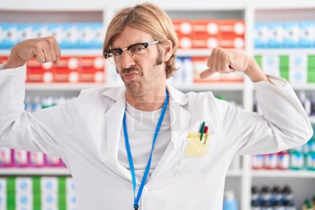 Photo for Caucasian man with mustache working at pharmacy drugstore showing arms muscles smiling proud. fitness concept. - Royalty Free Image