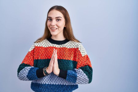Photo for Young hispanic girl standing over blue background praying with hands together asking for forgiveness smiling confident. - Royalty Free Image