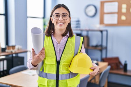 Photo for Hispanic girl architect holding build project blueprints smiling and laughing hard out loud because funny crazy joke. - Royalty Free Image