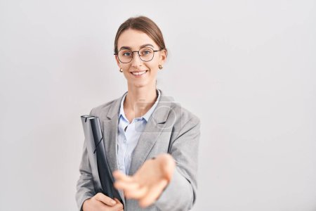 Photo for Young caucasian woman wearing business clothes and glasses smiling cheerful offering palm hand giving assistance and acceptance. - Royalty Free Image