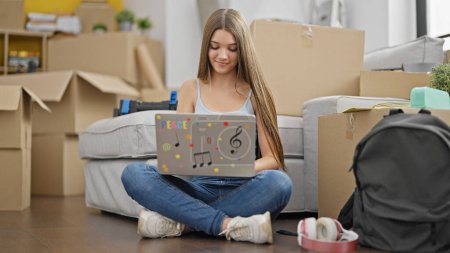 Photo for Young beautiful girl student using laptop sitting on floor at new home - Royalty Free Image