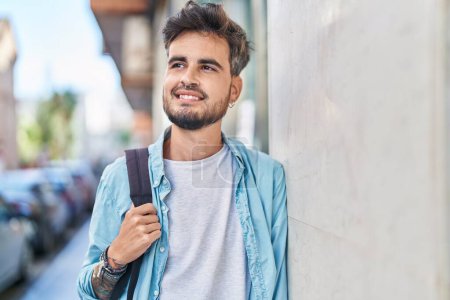Téléchargez les photos : Young hispanic man student smiling confident wearing backpack at street - en image libre de droit