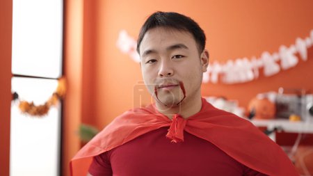 Téléchargez les photos : Young chinese man wearing devil costume having halloween party at home - en image libre de droit