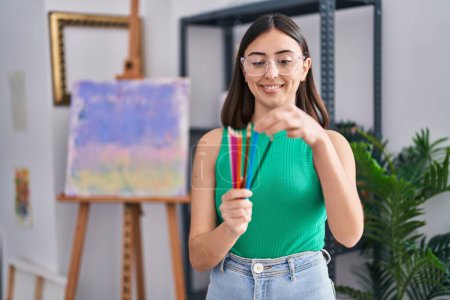 Téléchargez les photos : Jeune femme hispanique tenant des crayons de couleur debout au studio d'art - en image libre de droit