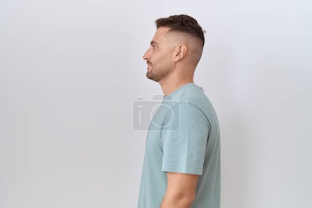 Photo for Hispanic man with beard standing over white background looking to side, relax profile pose with natural face and confident smile. - Royalty Free Image