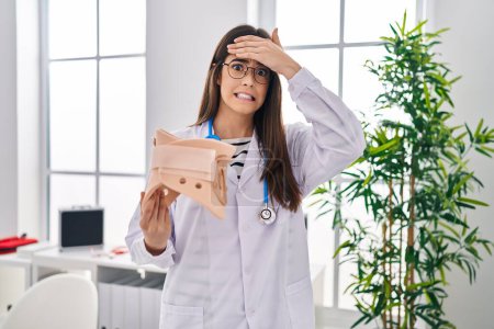 Photo for Young brunette doctor woman holding cervical neck collar stressed and frustrated with hand on head, surprised and angry face - Royalty Free Image