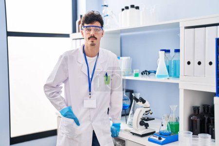 Téléchargez les photos : Jeune homme caucasien scientifique debout avec une expression détendue au laboratoire - en image libre de droit