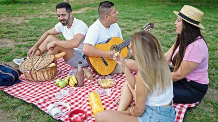 Foto de Grupo de personas tocando la guitarra haciendo picnic en el parque - Imagen libre de derechos